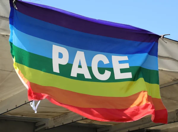 平和を意味し非暴力を象徴し戦争を象徴するイタリア語の大きな単語Paceと多色の旗 — ストック写真