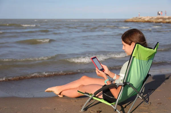 若い女の子は夏に海でリラックスしたデッキチェアで本を読んでいます — ストック写真