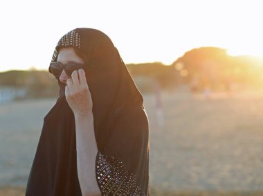 Çölde siyah güneş gözlüklü genç bir Arap kadın.