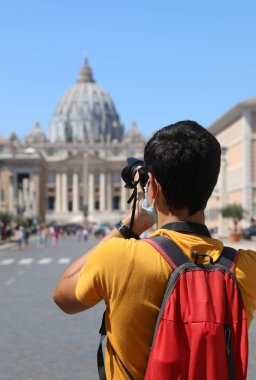 Yazın Roma 'da kameralı genç fotoğrafçı ve arka planda Aziz Peter Bazilikası