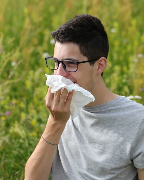 草にアレルギーがあるからハンカチでメガネをくしゃみをする少年 — ストック写真