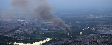 Akşamları nehir kenarındaki şehirde önemli bir yangın ve siyah yoğun duman.