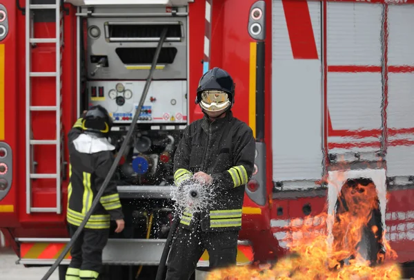 Tűzoltó Fúrás Közben Eloltja Tüzet Tűzoltókocsit Háttérben — Stock Fotó