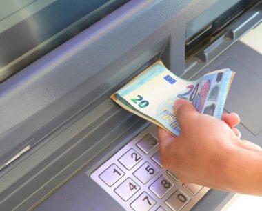 ATM ve euro cinsinden banknotlar ve bir çocuğun eli.