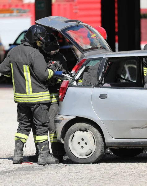 İtfaiyeciler çarpışan bir arabanın metal levhasını kırparken trafik kazasından sonra güçlü bir hidrolik makasla kesiyorlar.
