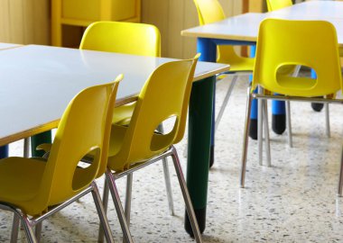 Tatil sırasında çocuklar olmadan okulun içinde sarı sandalyeler.