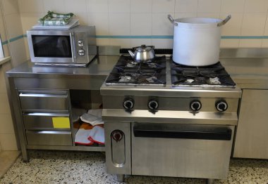 Sobanın üstünde büyük bir alüminyum kap ve aşılama hazırlıkları için bir çaydanlık olan bir sanayi mutfağının içinde.