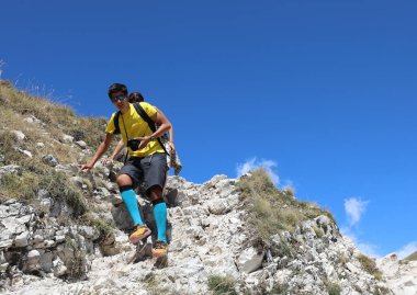 Gözlüklü ve kameralı genç yazın yürüyüş yaparken engebeli bir dağ yolunda