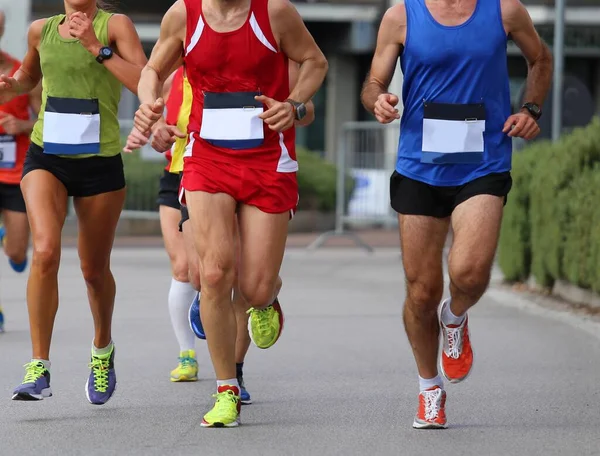group of athletic runners during the foot race in the city on the asphalt road and sportswear and running shoes
