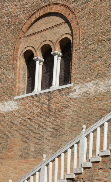 Eski bir binanın duvarında üç pencere ve merdiven çıkıntısı var.