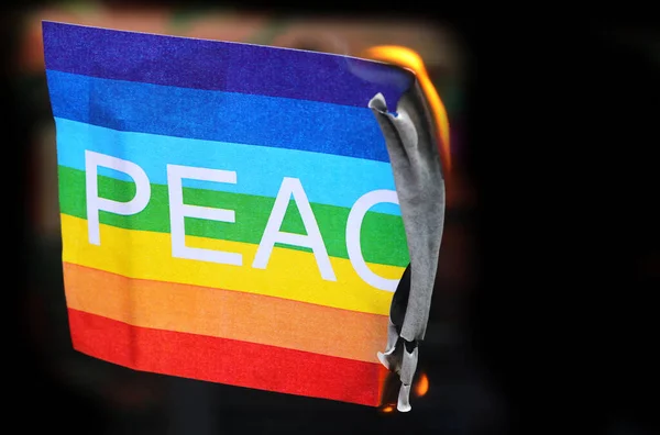 破壊と戦争の炎の象徴で燃える虹と大きな文字の色の平和旗 — ストック写真