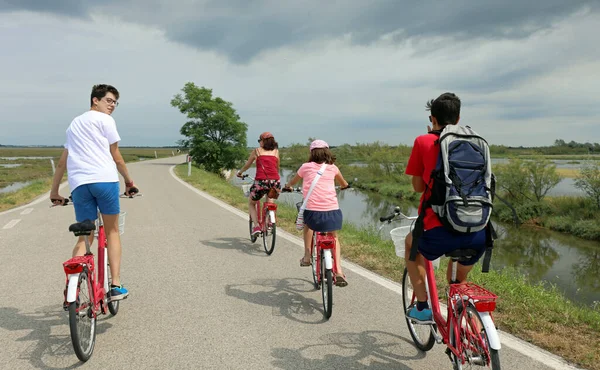 family of four during the bike ride on the bike path and the lagoon with brackish water