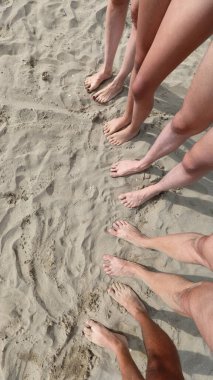 seen from above ten feet on the sandy beach of a five person family with father mother and three children