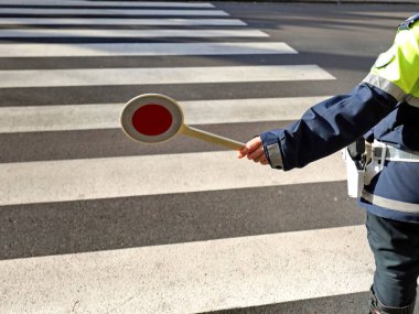 Polis trafiği düzenlemek için yaya geçidindeki arabaları durdurur.
