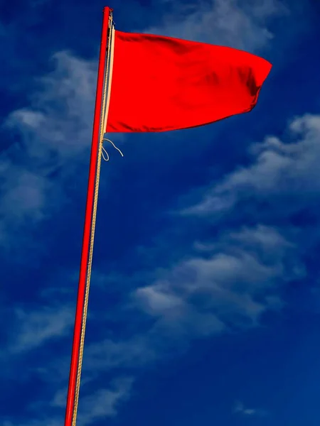 Czerwona Flaga Sygnalizuje Niebezpieczeństwo Bardzo Wzburzonego Morza Błękitnym Niebie — Zdjęcie stockowe
