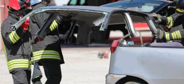 İtfaiyeciler otoyoldaki kazadan sonra hasar gören bir arabanın kaputunu çıkarırken...