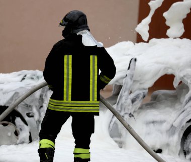brave firefighter after extinguishing the burning car which is now full of extinguishing white foam
