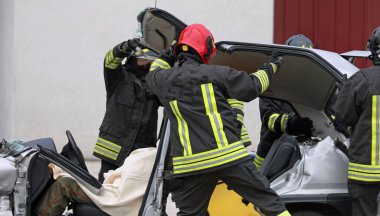 after the road accident the firefighters remove the hood from the car to free the injured person from the twisted metal sheets of the crashed vehicle