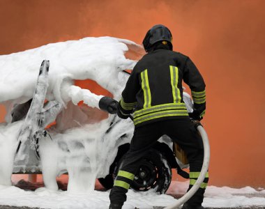 Firefighter exercise extinguishing the car fire by spreading the foam with the hydraulic hose