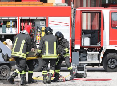 İtfaiyeciler trafik kazasından sonra yaralı adamı sedyeyle taşıyorlar.