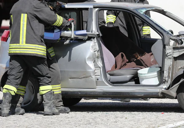 firefighters working group cutting the sheets of the crashed car with a powerful hydraulic shear to free the injured after the car accident