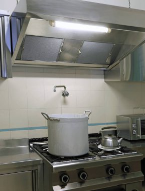 Endüstriyel mutfak, ocağında metal bir tencere ve çaydanlık var.