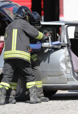 firefighters cutting the sheets of the crashed car with a powerful hydraulic shear to free the injured after the car accident