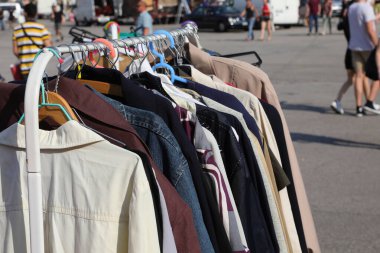 many used clothes for sale in the clothing stall in the outdoor flea market