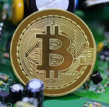 Bir devrenin elektronik bileşenlerinin ortasında bitcoin kripto para sembolü olan altın sikke