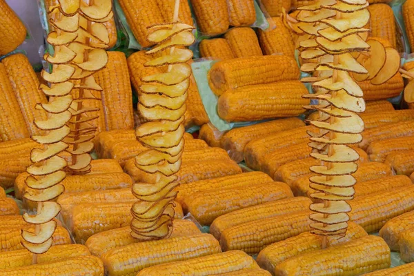 Many Yellow Cellophane Wrapped Corn Cobs Many Skewers Fried Potatoes — Foto Stock