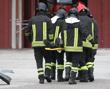 group of firefighters who help the injured person after the road accident and transport him on a stretcher to the hospital
