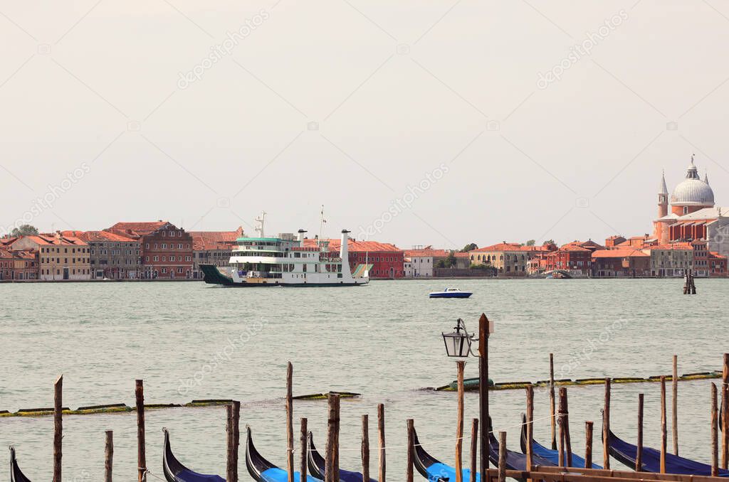 ship for the transport of cars traveling in the Giudecca canal near the island of Venice and moored gondolas