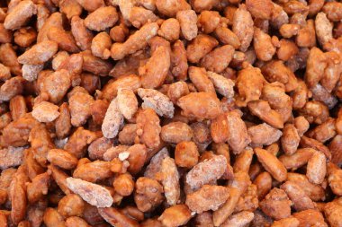 Yüzlerce kavrulmuş bademin arkaplanı ve tezgahta üzerinde karamelize şeker var.