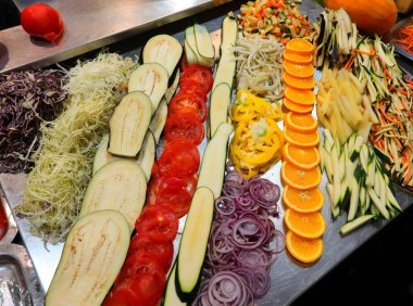 Endüstriyel kantinin restoranında yemek hazırlamak için kesilmiş bir sürü sebzeli çelik masa.