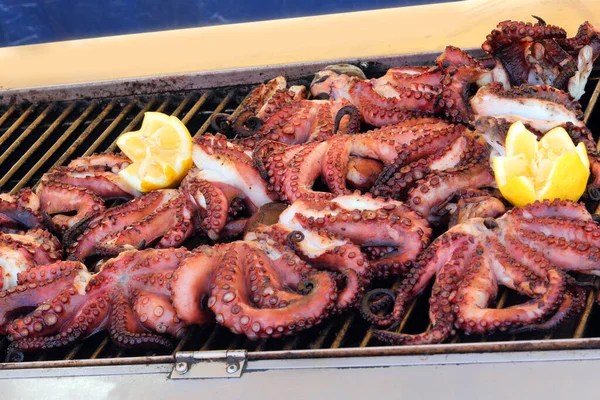 cooked octopus with many tentacles on the metal grill at fish restaurant
