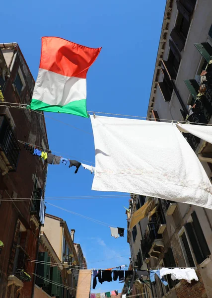 ITALIAN flag and the clothes hung out to dry between the houses of the city in the sunny day
