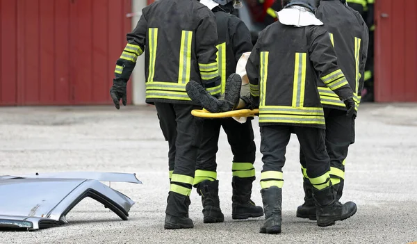 Stretcher with injured person and team of firefighters during rescue after the car accident