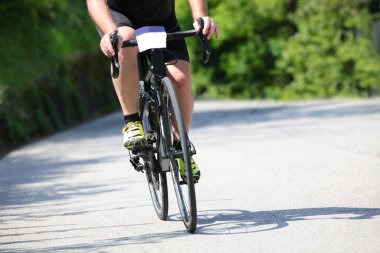 Yazın köy yollarında yapılan eğitim sırasında motosikletli yalnız bir bisikletçi.