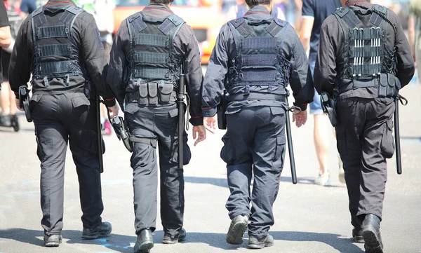 patrols of four policemen in riot gear with flak jackets and batons while watching the riot in the city