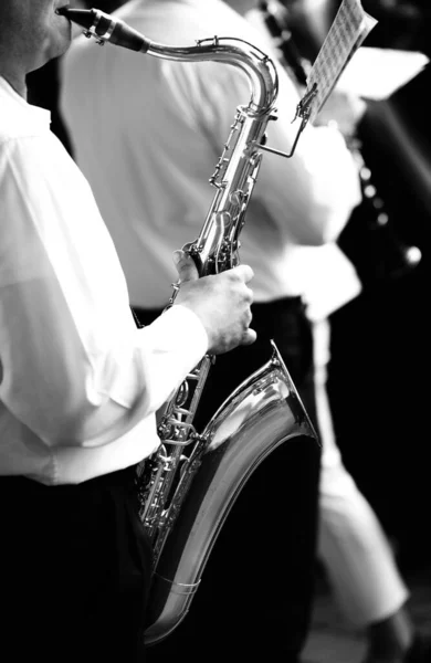 sax player while playing the instrument in the marching band during a concert in black and white effect toned