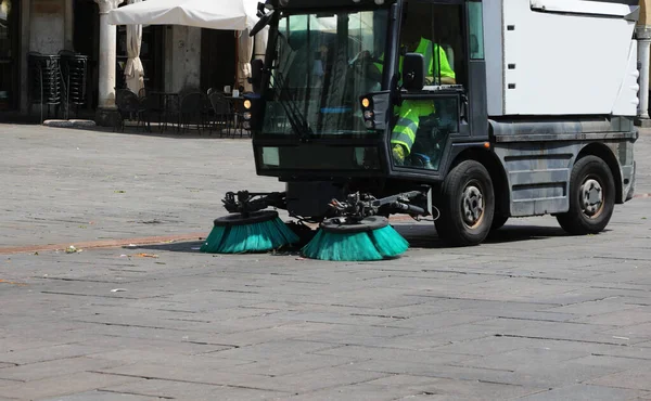 small van for cleaning the city square with the large industrial brushes in motion