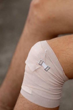 Burkulmadan sonra yaralanan eklem yerinin korunması için elastik bir bantla çocuğun dizi.