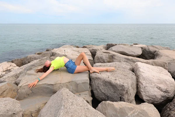 Young Girl Fluorescent Green Shirt Jeans Shorts Sunbathing Rocks Sea — Zdjęcie stockowe