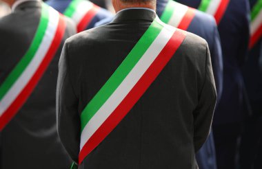 Üç renkli yeşil beyaz ve kırmızı kuşaklı resmi tören sırasında zarif elbiseli pek çok İtalyan belediye başkanı