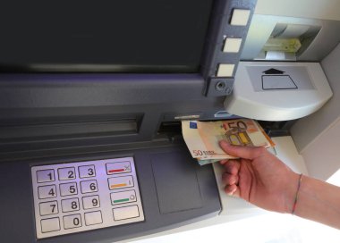 human hand taking euro banknotes from an ATM after typing the secret code