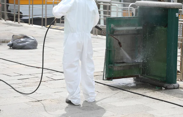 sanitizer worker During the cleaning of street furniture with a powerful jet of pressurized WATER during lockdown