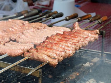 Restoranın yanan közlerinin üzerinde domuz eti ve tavuk sosisleriyle ızgara yapıyorlar.