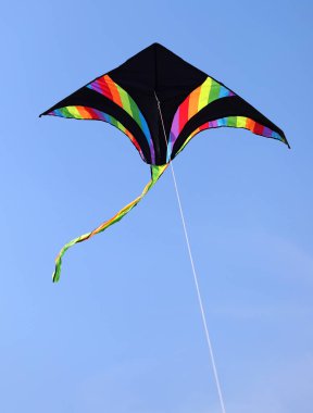 triangular-shaped kite in black and with multicolored bands that wants high in the sky tied to a string