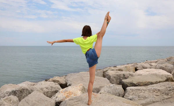 Young Girl Does Rhythmic Gymnastics Exercises Rocks Sea Jeans Shorts — Stockfoto