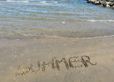 Deniz kıyısındaki kumsalda büyük harflerle 